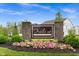A welcoming 'Trails at Grassy Creek' sign surrounded by vibrant pink flowers and lush greenery at 10118 Falls Canyon Ln, Indianapolis, IN 46229