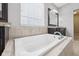 A bathroom with a soaking tub with stone surround and chrome fixtures at 10806 Solis Cir, Fishers, IN 46038