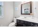 Powder room featuring a wood vanity with a white sink, a mirror, and a window for natural lighting at 10806 Solis Cir, Fishers, IN 46038