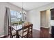 Inviting dining area with hardwood floors, large window, elegant chandelier and a wooden table with six chairs at 10806 Solis Cir, Fishers, IN 46038