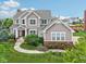 Beautiful two-story home with manicured lawn, colorful landscaping, and a paved walkway at 10806 Solis Cir, Fishers, IN 46038