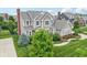 Aerial view of a tan, two-story home featuring a manicured lawn, landscaping, and a private driveway at 10806 Solis Cir, Fishers, IN 46038