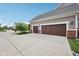 Attached two-car garage featuring brown doors, a concrete driveway, and brick accents under a blue sky at 10806 Solis Cir, Fishers, IN 46038
