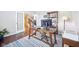 Home office with a wooden desk, blue rug, white french doors, and a bookcase on hardwood floors at 10806 Solis Cir, Fishers, IN 46038