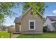 Side view of the home showcasing the architecture and landscaping, surrounded by a chain link fence at 1106 N Sheffield Ave, Indianapolis, IN 46222