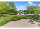 Charming backyard with a brick patio and fire pit area, surrounded by lush landscaping and a tranquil pond at 11761 Darsley Dr, Fishers, IN 46037
