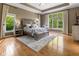 A spacious main bedroom featuring a large window, tray ceiling, and hardwood floors at 11761 Darsley Dr, Fishers, IN 46037