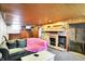 Finished basement offers stairs, a sofa, a brick fireplace, and a wood paneled ceiling at 1411 N Kenmore Rd, Indianapolis, IN 46219