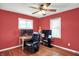 Cozy bedroom with red walls, ceiling fan, desk with computers, and a television on a stand at 1411 N Kenmore Rd, Indianapolis, IN 46219