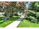 View of a cozy home with a manicured lawn, mature trees, and a welcoming walkway at 1411 N Kenmore Rd, Indianapolis, IN 46219
