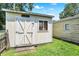 Shed on a well-manicured lawn with a white door and window at 1411 N Kenmore Rd, Indianapolis, IN 46219