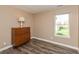 Neutral bedroom with a wooden dresser, lamp, and a large window allowing natural light at 1450 Millridge Dr, Greenwood, IN 46143