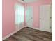Bright pink bedroom with wood floors, two white doors, and a sheer curtain at 1450 Millridge Dr, Greenwood, IN 46143