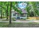 View of a charming home with a small porch and surrounding greenery, framed by mature trees at 1511 E Edwards Ave, Indianapolis, IN 46227