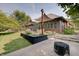 Relaxing backyard with a brick house, covered patio, lush greenery and a firepit at 214 W Stoney Trl, Greenfield, IN 46140