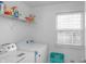 Bright laundry room with a washer, dryer, storage shelf, and natural light from a window at 2211 Willowview Dr, Indianapolis, IN 46239
