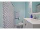This light blue bathroom features a shower with patterned curtain, towel rack, and vanity sink at 2309 Maple St, Columbus, IN 47201