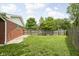 Wide shot of the backyard featuring a wood fence, grassy area and shade trees at 258 N Green Springs Rd, Indianapolis, IN 46214