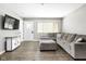 Bright living room with a large gray sofa, entertainment console, and laminate flooring at 258 N Green Springs Rd, Indianapolis, IN 46214