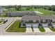 Aerial view showcasing townhomes with attached garages and lush green spaces with a pond in the background at 2892 Maricopa Blvd, Whitestown, IN 46075