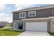 A gray and brick townhouse showcases a large garage door, a covered grill, and a green lawn at 2892 Maricopa Blvd, Whitestown, IN 46075
