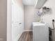 A laundry room features a washer and dryer, complemented by a white shelf, a cabinet, and wood-look flooring at 2892 Maricopa Blvd, Whitestown, IN 46075