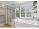 Bright bathroom featuring a soaking tub, glass enclosed shower, and a view to the outside at 3823 Vanguard Cir, Carmel, IN 46032