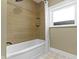 Tiled bathroom with a bathtub, shower, and window providing natural light at 4002 Guilford Ave, Indianapolis, IN 46205