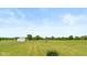 Expansive grassy land featuring a metal outbuilding and a backdrop of lush trees under a vast, clear sky at 4287 Gibbs Rd, Danville, IN 46122