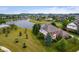 Aerial view of a red brick home with mature trees and landscaping with a neighborhood lake nearby at 4617 S Cobblestone Dr, Zionsville, IN 46077