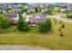 Aerial view of a brick home with a patio and fire pit surrounded by green lawns and mature trees at 4617 S Cobblestone Dr, Zionsville, IN 46077