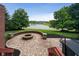 A brick patio with a fire pit and a hot tub is situated next to a scenic pond in the backyard at 4617 S Cobblestone Dr, Zionsville, IN 46077