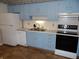 Kitchen featuring blue cabinets, white appliances, and linoleum flooring at 509 Eberhart Dr, Shelbyville, IN 46176