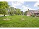 Great backyard featuring green grass, mature trees, a swing set, and a fire pit at 5695 N Red Oak Dr, Greenfield, IN 46140
