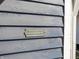 Humorous plaque on weathered blue siding: 