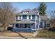 Charming two-story home features a covered front porch, gray roof, and a blue exterior at 6101 Broadway St, Indianapolis, IN 46220