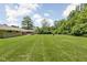 Expansive backyard with lush lawn, mature trees, and view of the home's exterior at 6464 Whitley Ln, Indianapolis, IN 46260