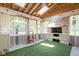 Relaxing sunroom with stone fireplace, artificial turf, skylights, and backyard views at 6464 Whitley Ln, Indianapolis, IN 46260