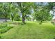 Expansive backyard featuring a fire pit, mature trees, lawn, and a black fence at 6644 Mcfarland Rd, Indianapolis, IN 46227