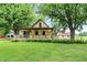 Inviting home featuring a charming front porch, lush green lawn, and mature trees at 6644 Mcfarland Rd, Indianapolis, IN 46227