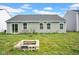 View of the backyard, showcasing a fire pit, chairs on the patio, sliding glass door, and manicured lawn at 7171 E Rising Sun S Cir, Camby, IN 46113