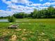 Backyard featuring a fire pit and garden beds overlooking a tranquil pond with scenic trees in the background at 7171 E Rising Sun S Cir, Camby, IN 46113