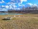 Backyard featuring a fire pit and garden beds overlooking a tranquil pond with scenic trees in the background at 7171 E Rising Sun S Cir, Camby, IN 46113