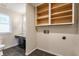 The combined laundry and bathroom features tile floor, open cabinet space, and connections for a washing machine and dryer at 8015 Ridgegate East Dr, Indianapolis, IN 46268