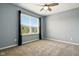 Bedroom with plush carpet, ceiling fan, and large window with dark curtains at 10606 Glenwyck Pl, Noblesville, IN 46060
