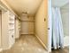 Carpeted walk-in closet adjacent to a bathroom featuring built-in shelving and a shower-tub combo at 10900 Clear Spring Dr, Camby, IN 46113