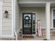 Covered front porch featuring door with glass and a small, decorative welcome sign at 11809 Redpoll Trl, Noblesville, IN 46060