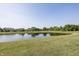 Scenic view of a community pond surrounded by lush greenery and residential homes on a clear, sunny day at 1283 Clairet, Westfield, IN 46074