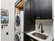 Laundry room features a stacked washer/dryer, modern black cabinets with gold accents, and a white countertop sink at 1345 Lewiston Dr, Westfield, IN 46074