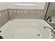 A relaxing bathtub features tile detail with a window for natural lighting at 13616 Whitten N Dr, Fishers, IN 46037